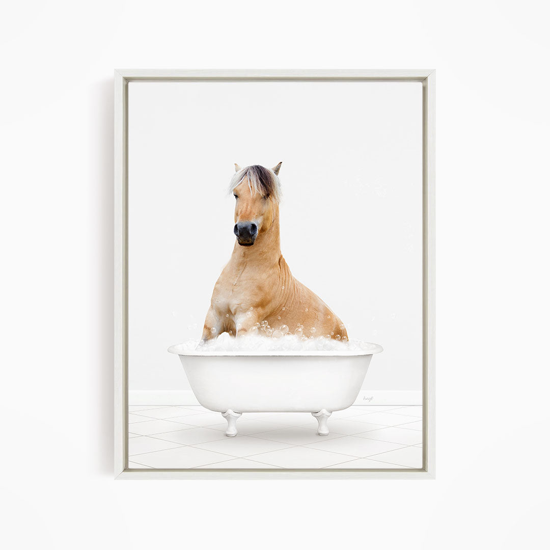 A brown horse sitting in a white bathtub filled with bubbles.
