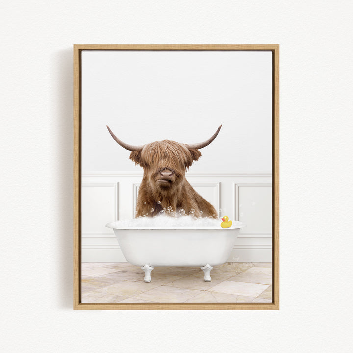 A brown cow with long horns is sitting in a white bathtub, with a yellow rubber duck floating in the water.