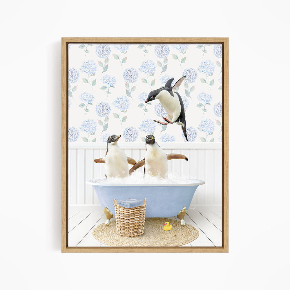 A framed image depicting two penguins sitting in a bathtub filled with water, surrounded by a blue floral patterned wall and a basket of rubber ducks.