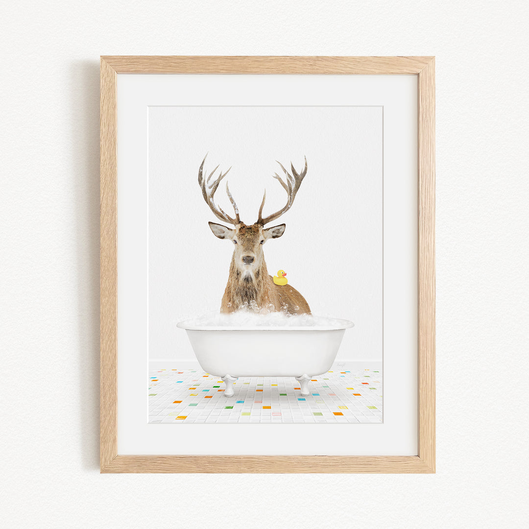 A deer with antlers is sitting in a white bathtub, with a yellow rubber duck perched on its head.