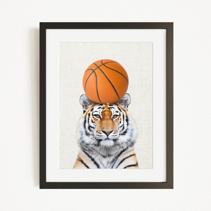 A tiger is sitting on a basketball, with the basketball positioned on top of its head.
