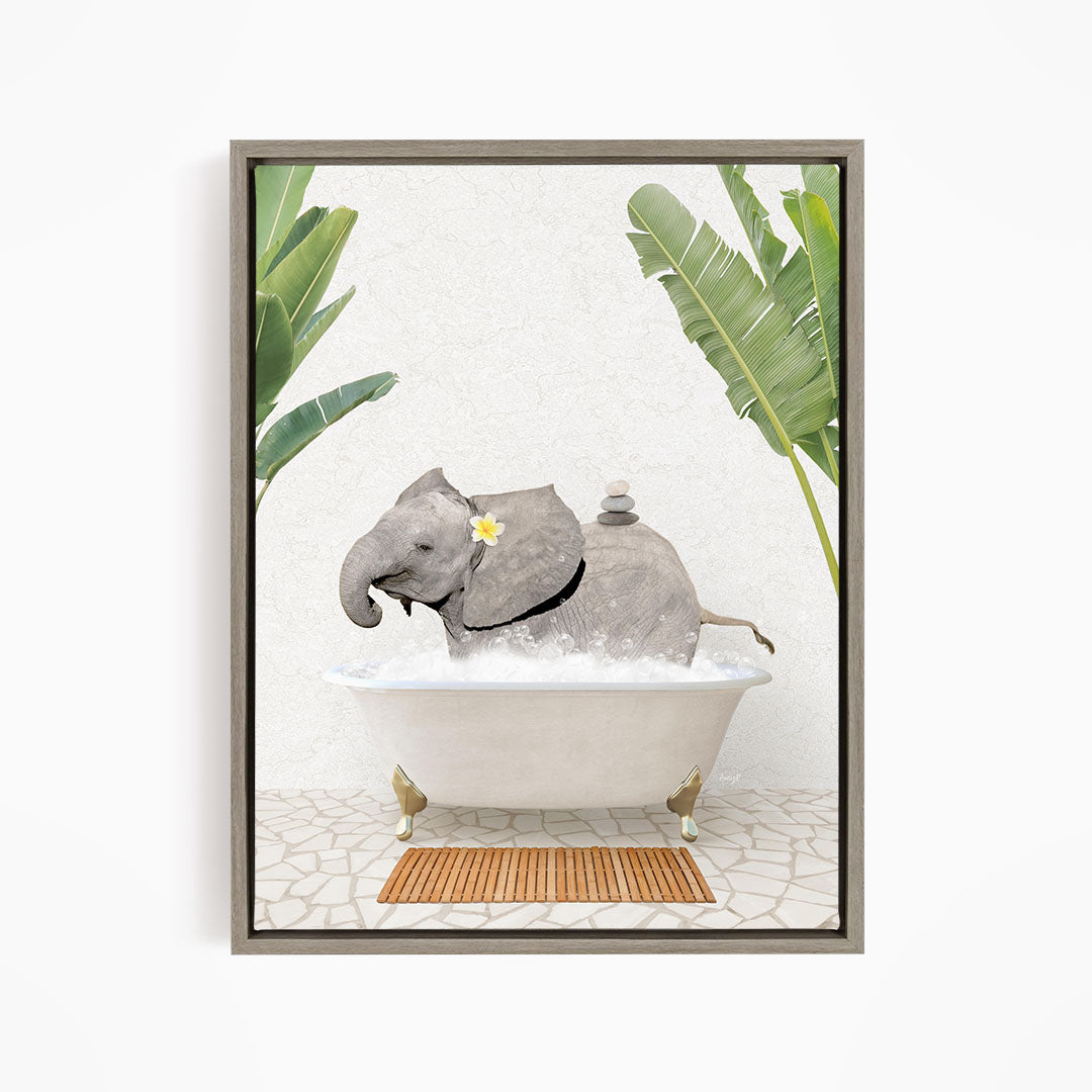 A gray elephant is sitting in a white bathtub filled with water, surrounded by green leaves and a wooden mat on the floor.