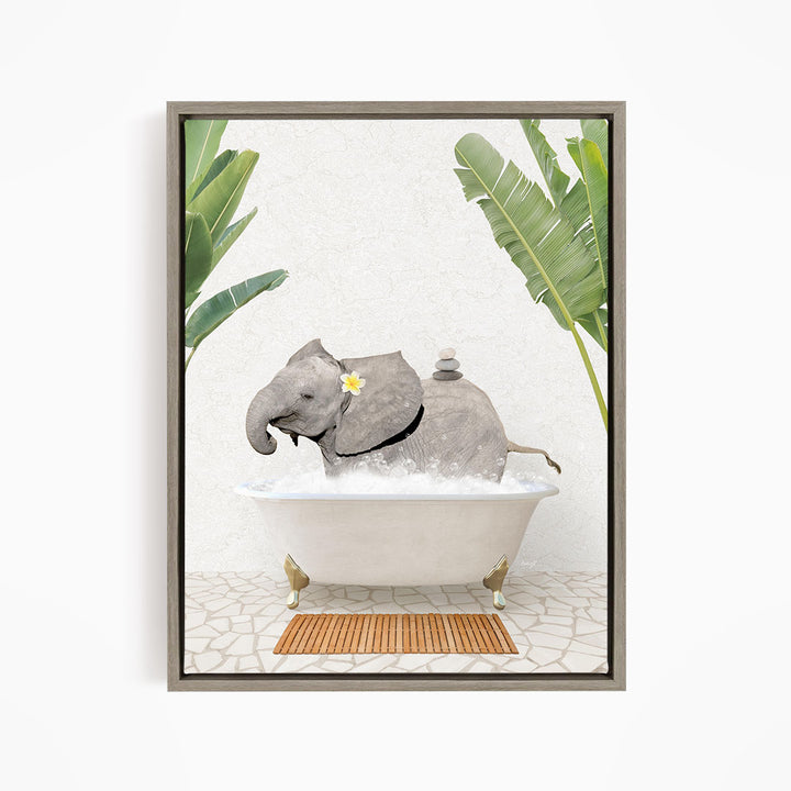 A gray elephant is sitting in a white bathtub filled with water, surrounded by green leaves and a wooden mat on the floor.