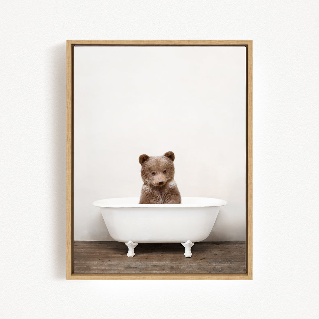A brown bear sitting in a white bathtub against a plain white background.