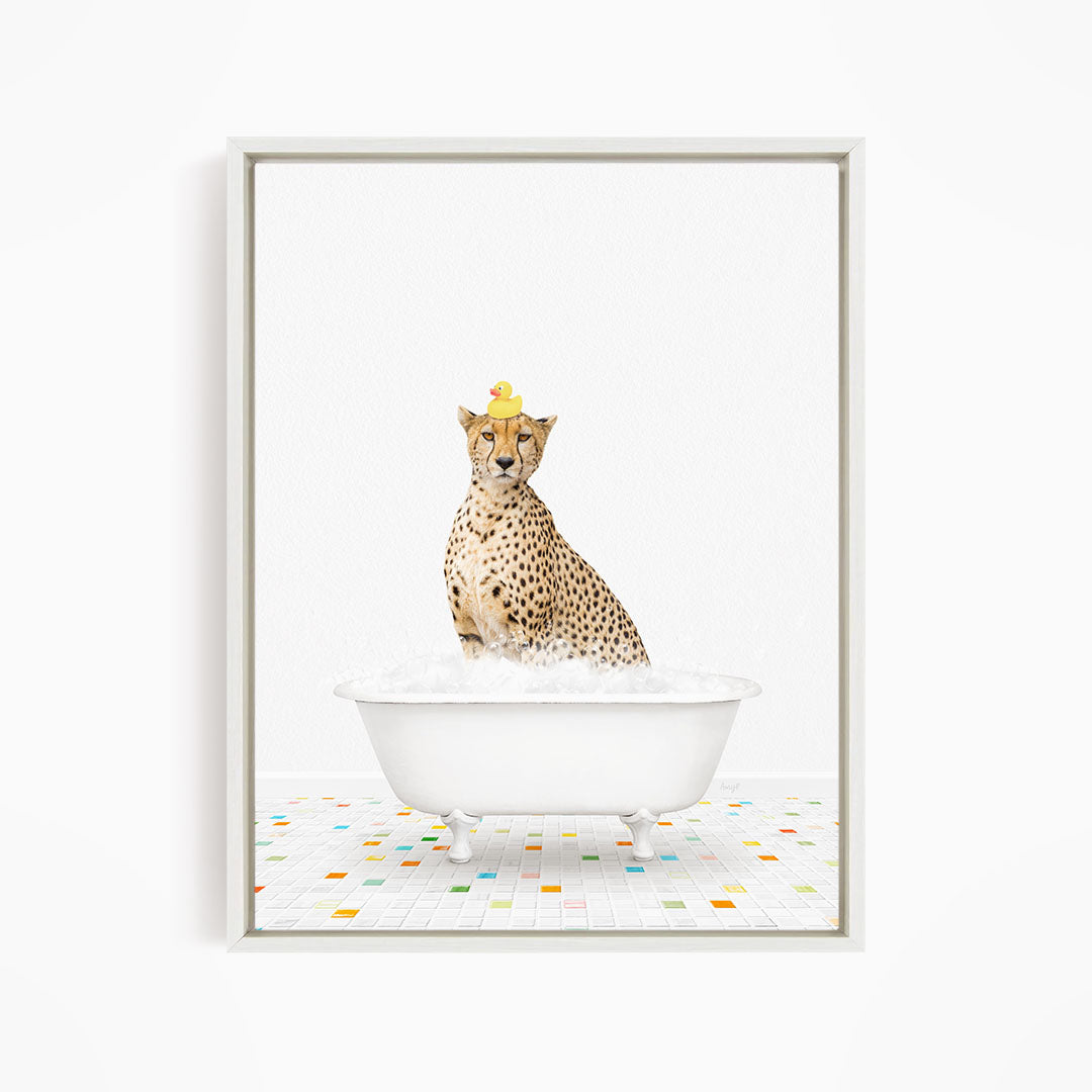 A cheetah sitting in a white bathtub filled with bubbles, with a rubber duck perched on its head.