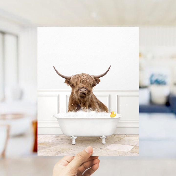 A brown cow with long horns is sitting in a white bathtub filled with bubbles, with a yellow rubber duck floating in the water.