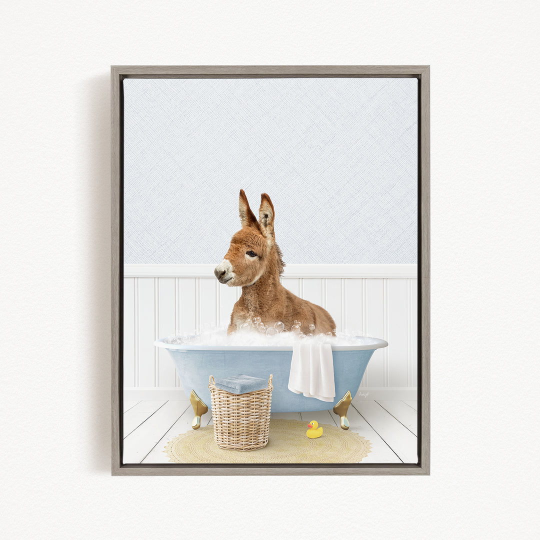 A donkey is sitting in a bathtub filled with water, surrounded by a yellow rubber duck and a wicker basket.