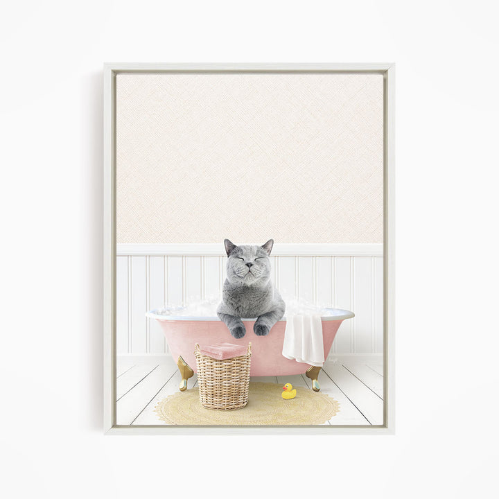 A gray cat sitting in a pink bathtub, surrounded by a yellow rubber duck and a wicker basket.