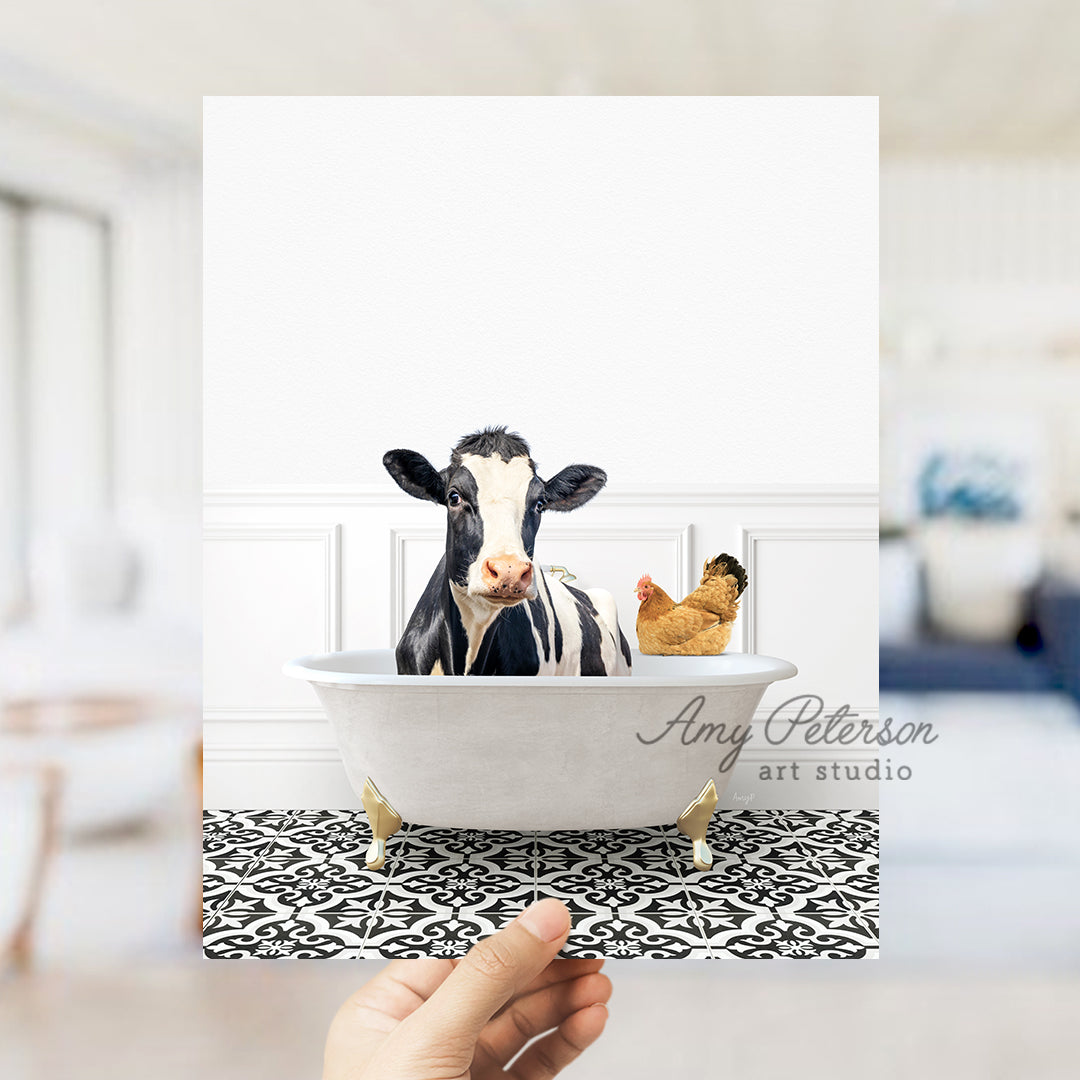 a hand holding a card with a picture of a cow in a bathtub