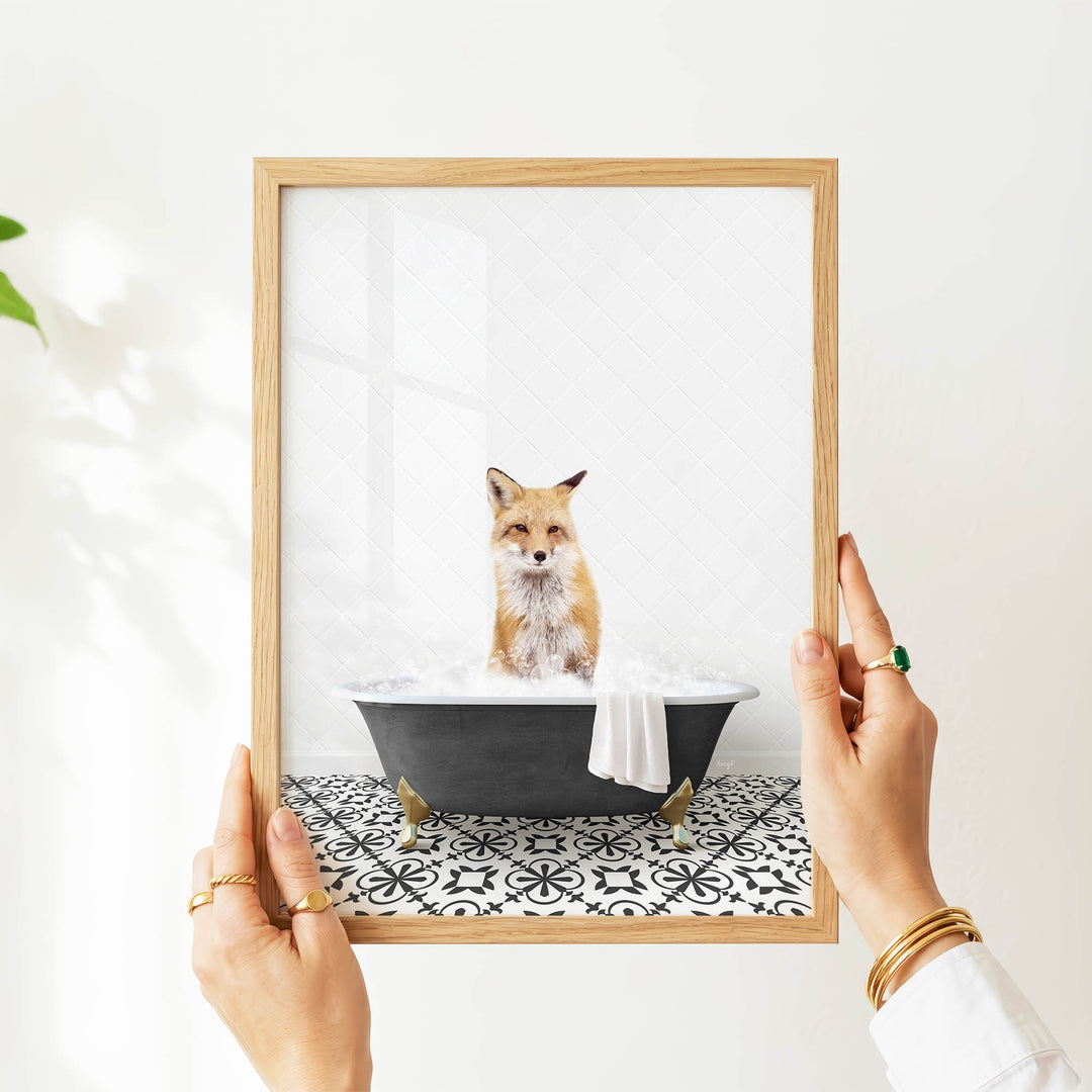 A person's hands are holding a framed picture of a cat sitting in a bathtub filled with water.