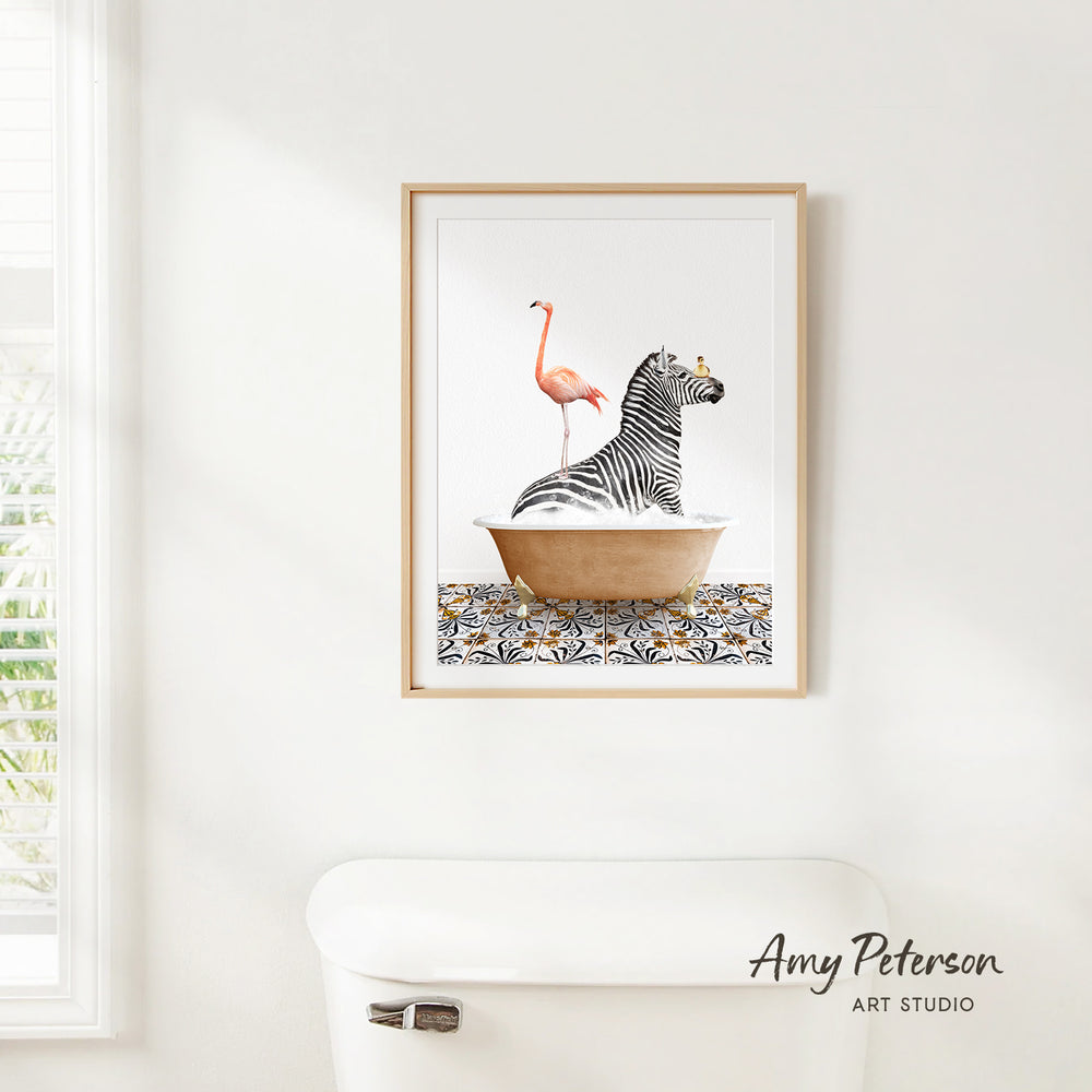 A framed print of a zebra sitting in a bathtub with a pink flamingo standing on its back, against a white wall.