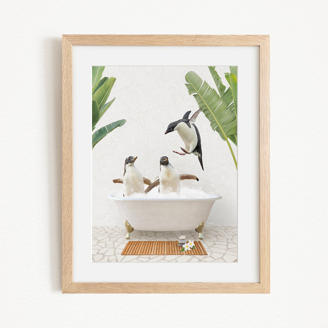A framed image depicting three penguins sitting in a bathtub, surrounded by tropical plants.