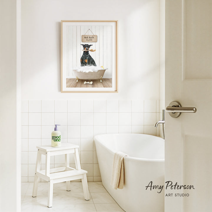 A framed picture of a dog sitting in a bathtub, with a sign above it that says "Hot bath $1.00". The bathroom has a white bathtub, a stool, and a towel hanging on the side of the tub.