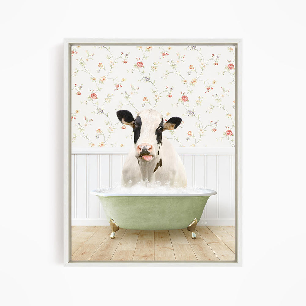 A black and white cow is sitting in a green bathtub filled with water, with a floral wallpaper in the background.