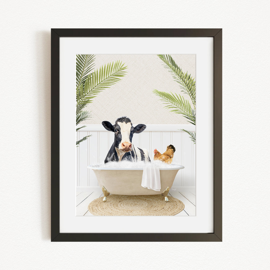 A framed image depicting a cow sitting in a bathtub, surrounded by tropical plants and a chicken.