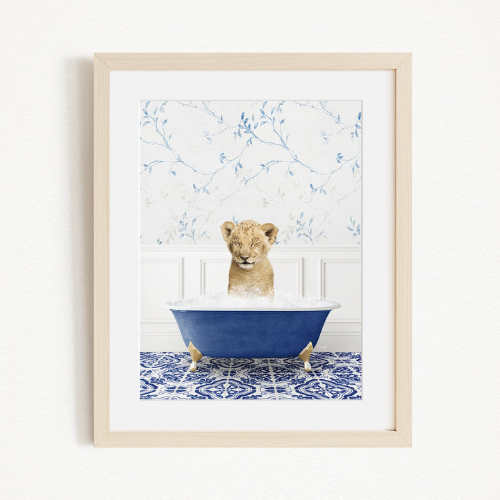 A young lion cub sitting in a blue bathtub filled with water, surrounded by a blue and white patterned rug.