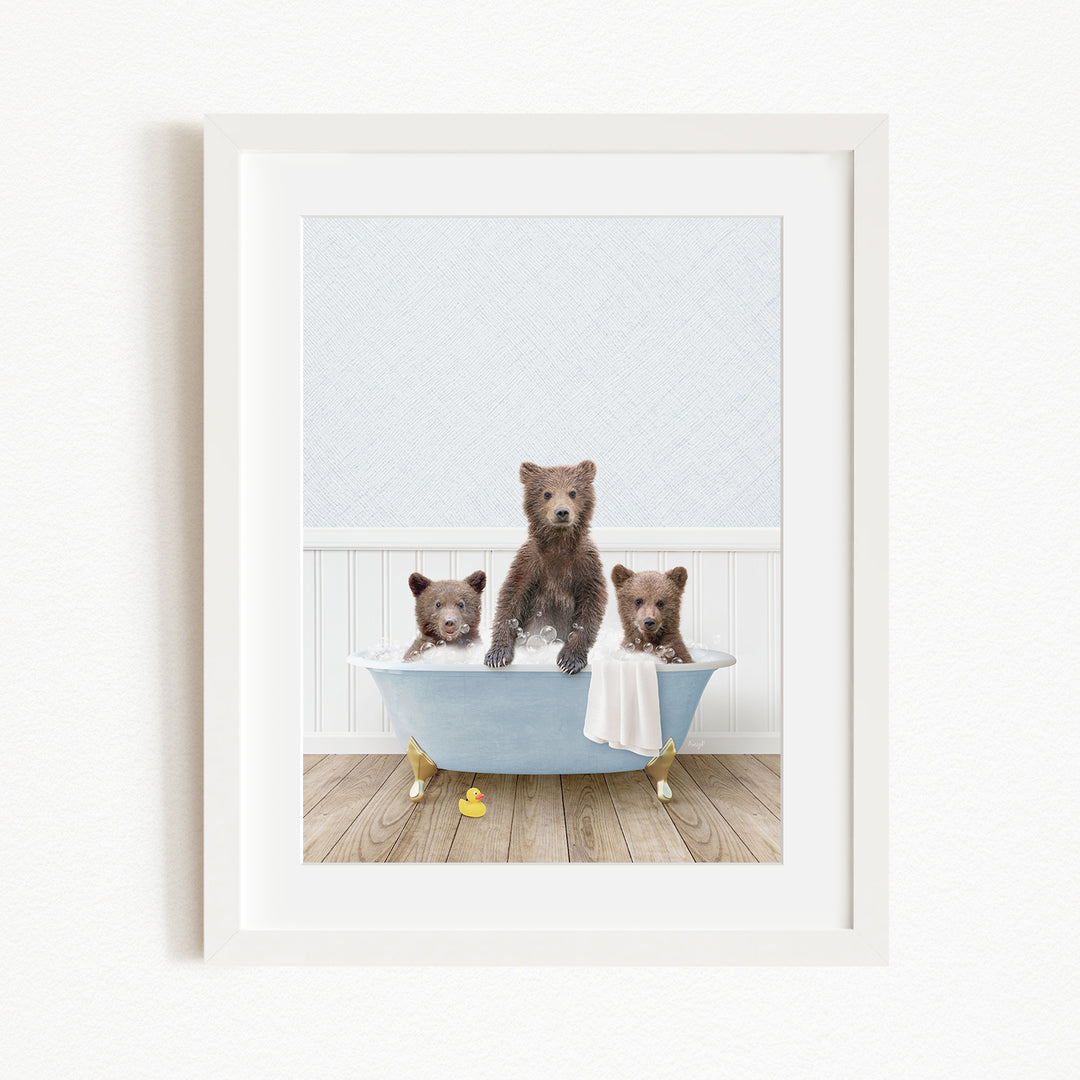 A framed image depicting three brown bears sitting in a blue bathtub, with one bear sitting on the edge of the tub and the other two bears sitting inside the tub.