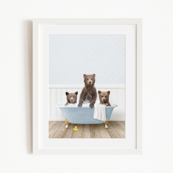 A framed image depicting three brown bears sitting in a blue bathtub, with one bear sitting on the edge of the tub and the other two bears sitting inside the tub.