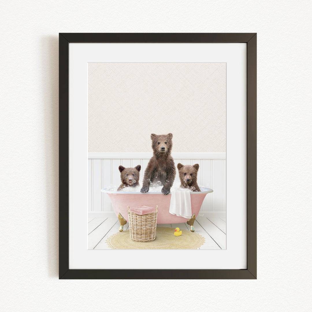A framed image depicting three bears sitting in a pink bathtub, with a yellow rubber duck floating in the water.