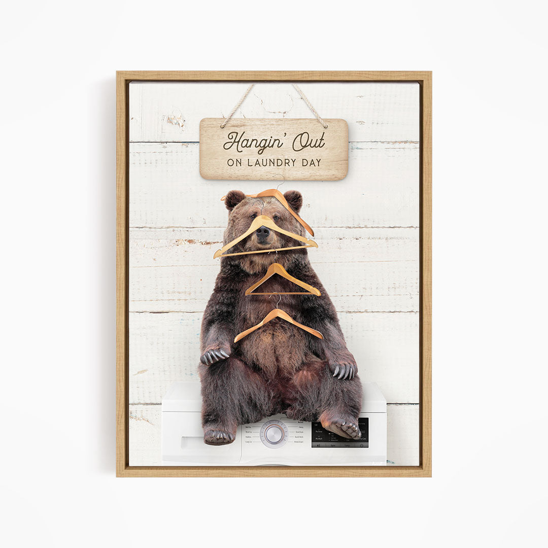 A framed image of a bear sitting on a washing machine, with a sign above it that says "Hangin' Out on laundry day".