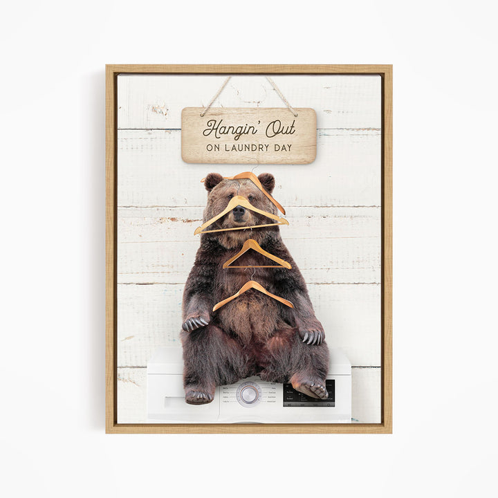 A framed image of a bear sitting on a washing machine, with a sign above it that says "Hangin' Out on laundry day".