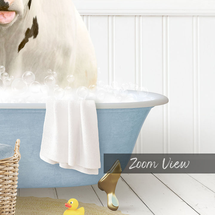 A white cow is sitting in a blue bathtub filled with bubbles, with a yellow rubber duck nearby.
