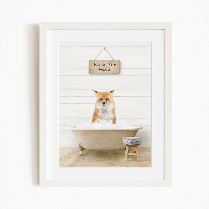 A framed image depicting a fox sitting in a bathtub, with a sign above that reads "Wash Your Face".