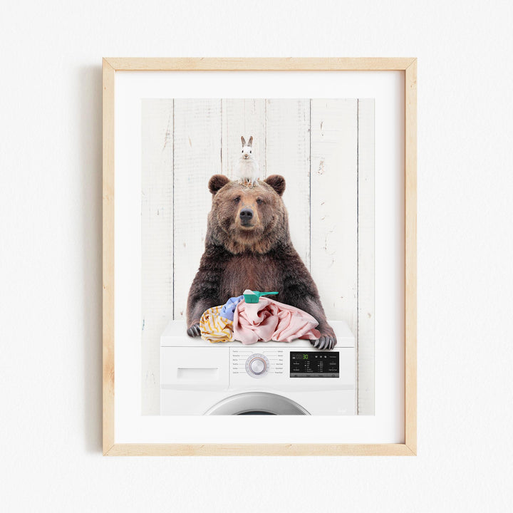 A brown bear sitting on top of a washing machine, with a white rabbit perched on its head.