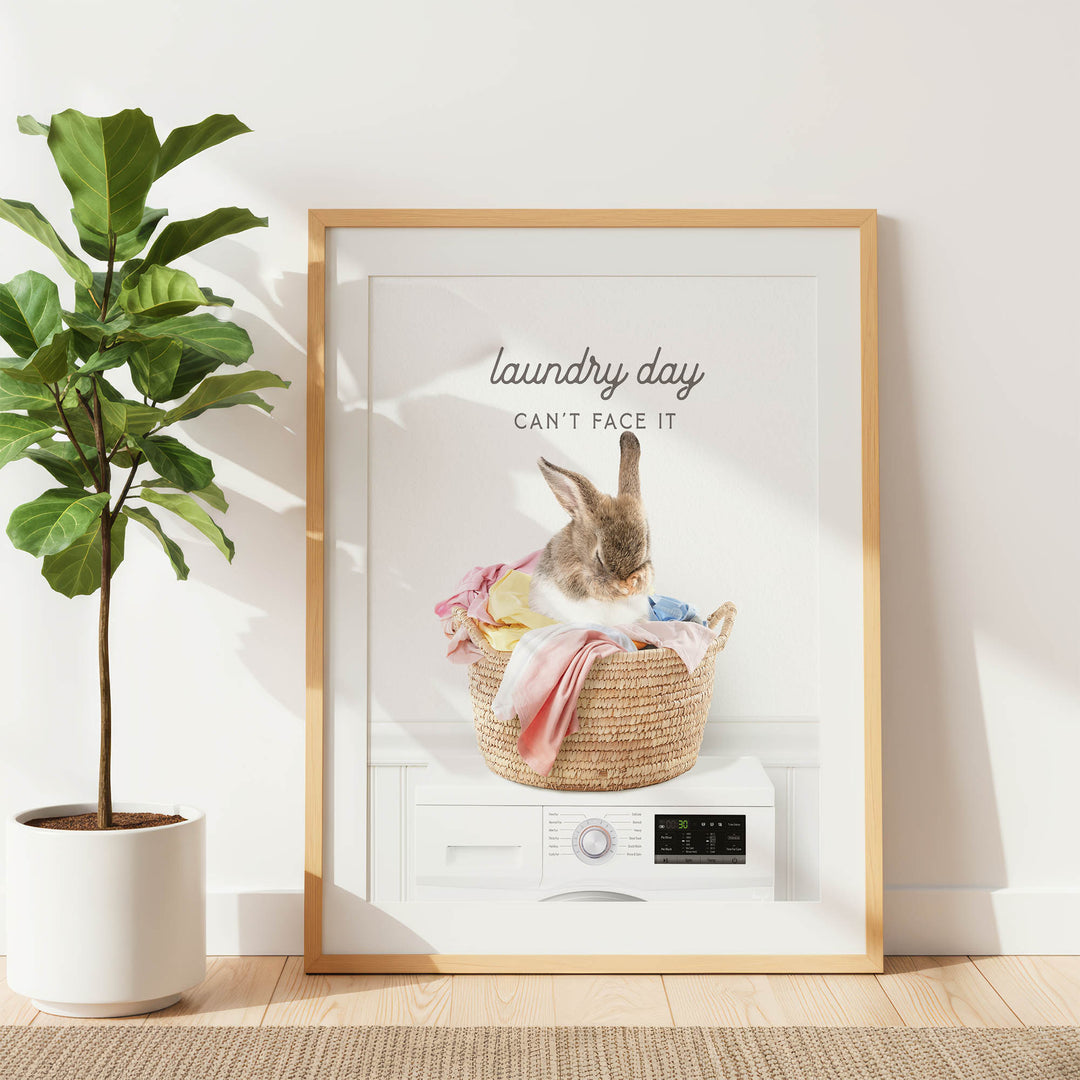 a framed poster with a rabbit sitting in a woven basket filled with laundry, accompanied by the text "laundry day can't face it".