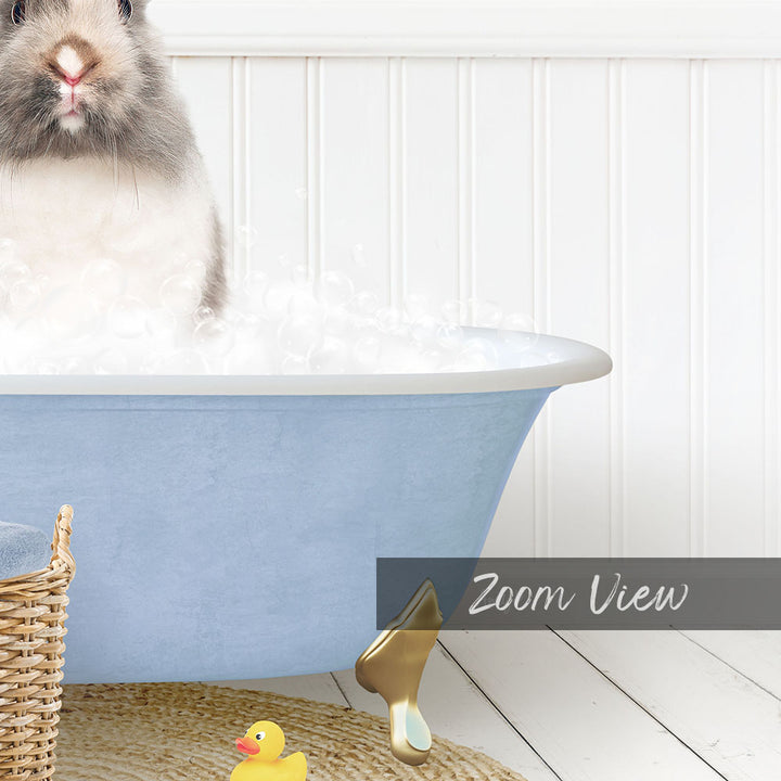 A gray and white rabbit sitting in a blue bathtub filled with bubbles, with a yellow rubber duck nearby and a basket on the floor.