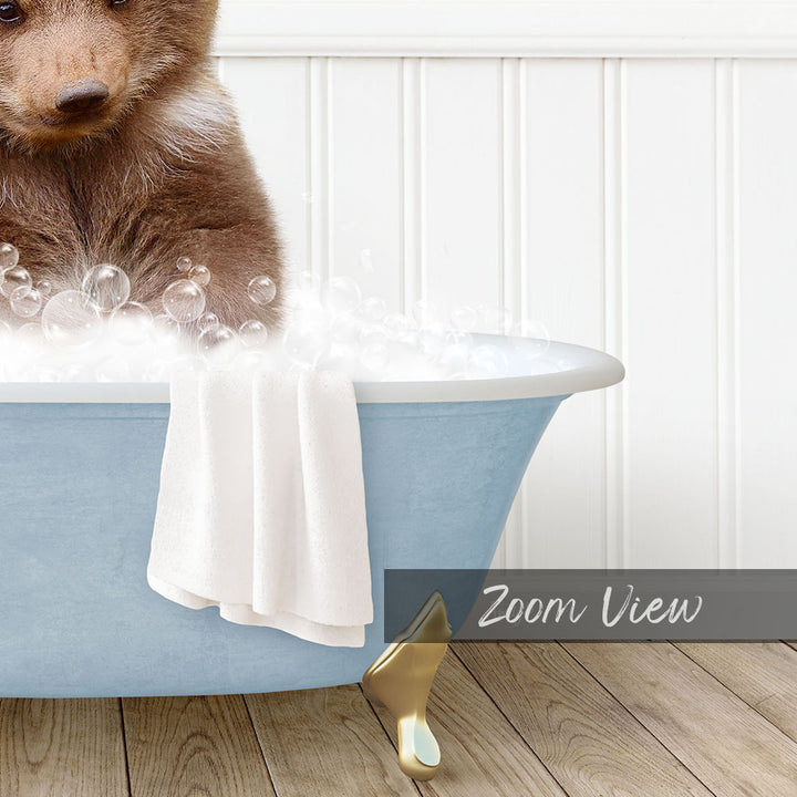 A brown bear sitting in a blue bathtub filled with bubbles, with a towel draped over the side and a "Zoom View" label below the image.