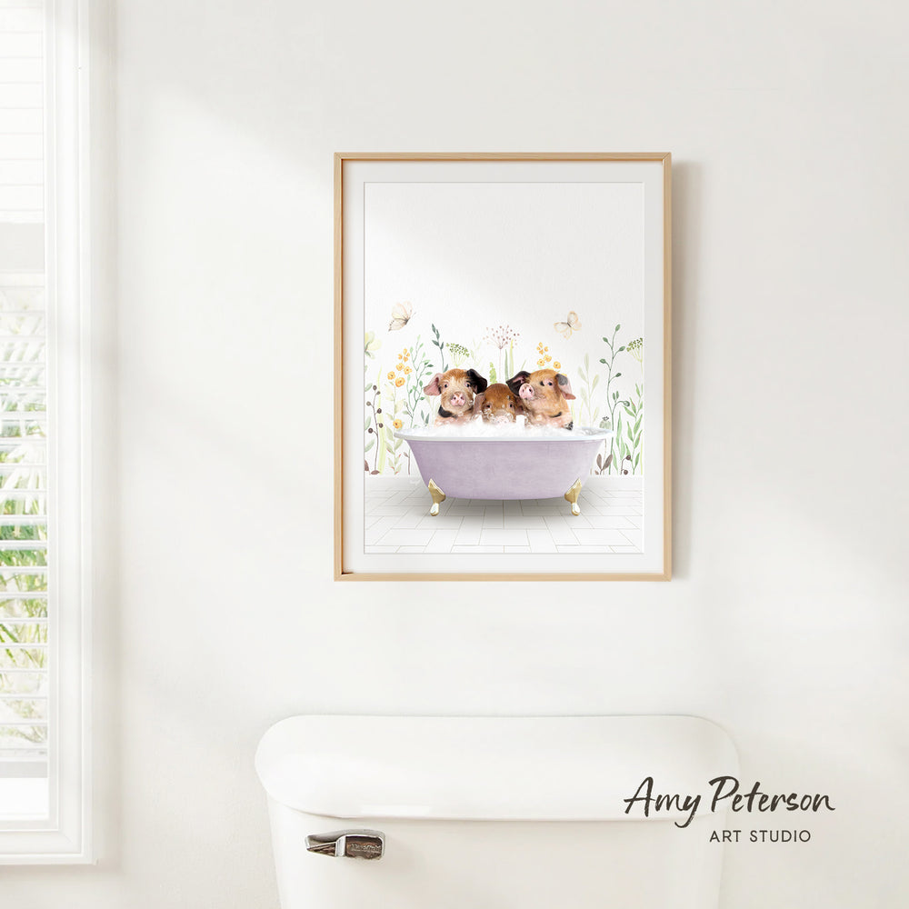 A framed illustration of two hamsters sitting in a bathtub, surrounded by flowers and butterflies, is hanging on a white wall.