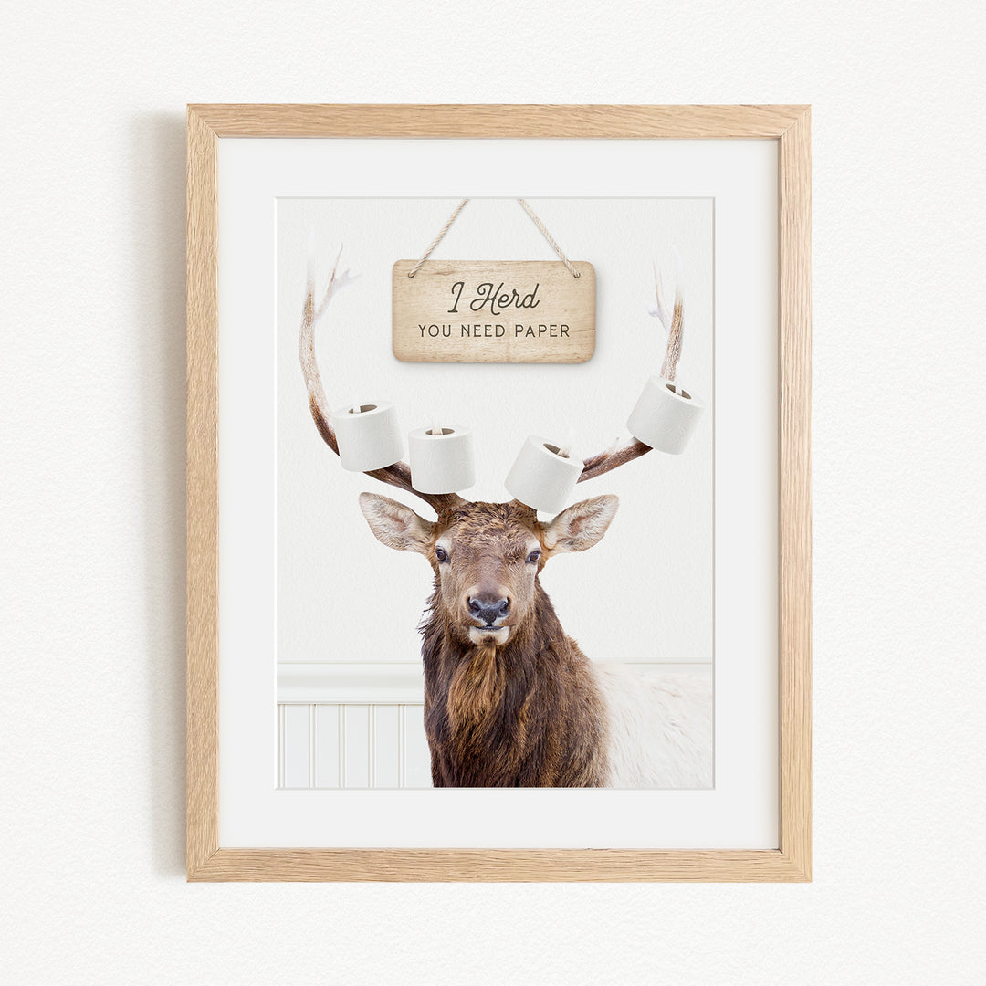 A framed image of a deer with antlers, displaying a sign that says "I herd you need paper".