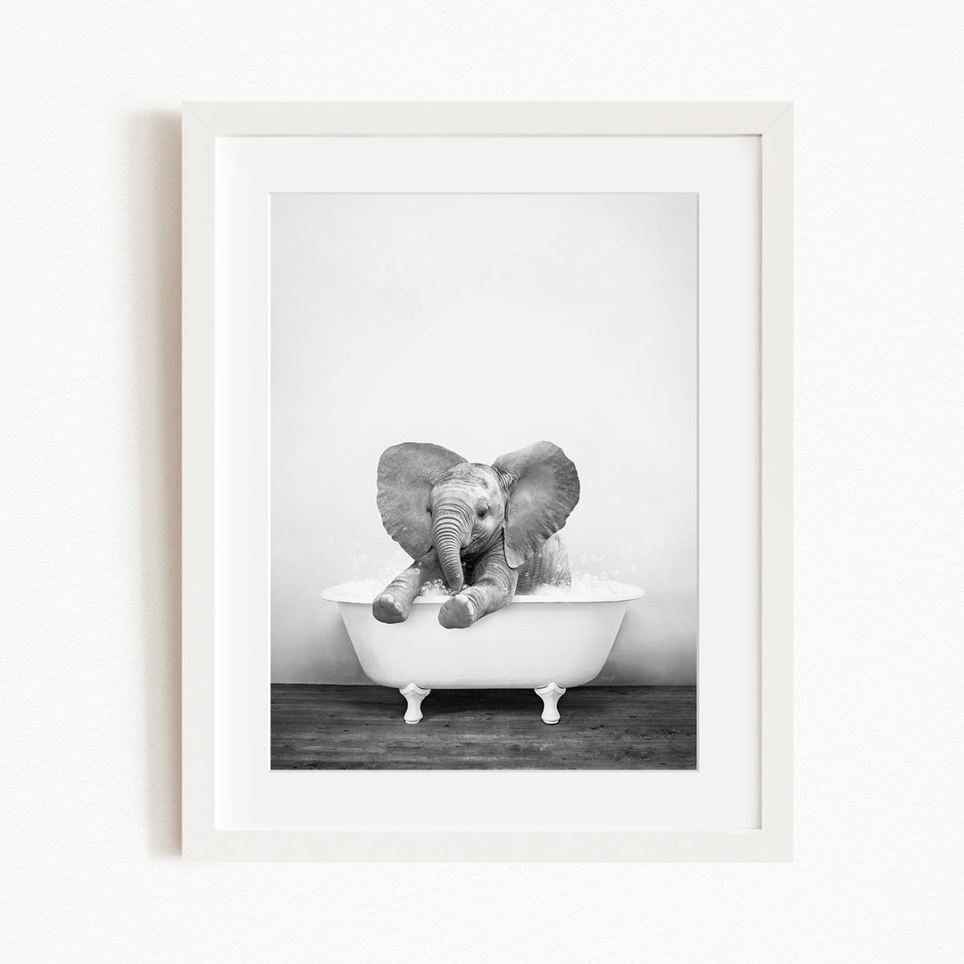 A baby elephant sitting in a white bathtub, enjoying a bath.