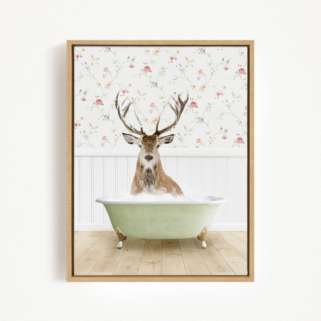 A deer with large antlers is sitting in a green bathtub filled with bubbles, against a floral wallpaper background.