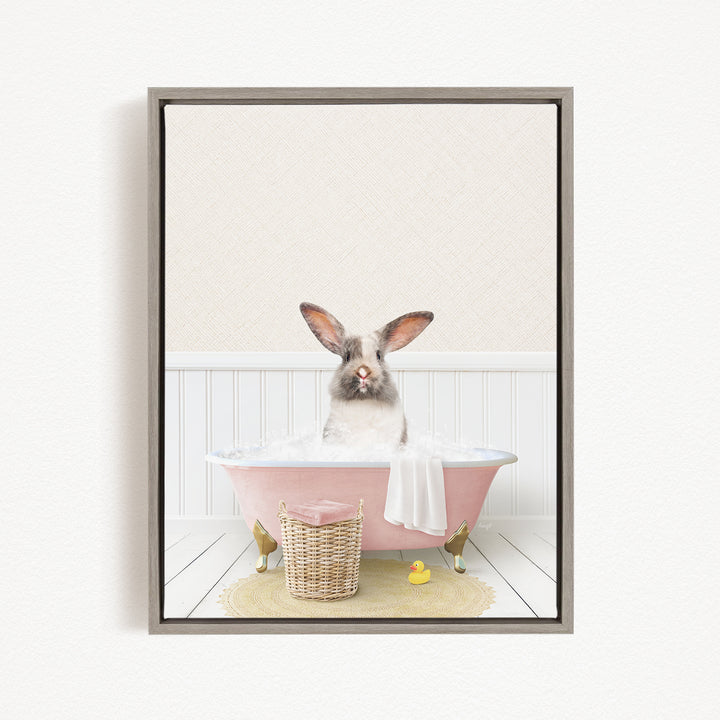 A white rabbit sitting in a pink bathtub filled with water, surrounded by a yellow rubber duck and a wicker basket.