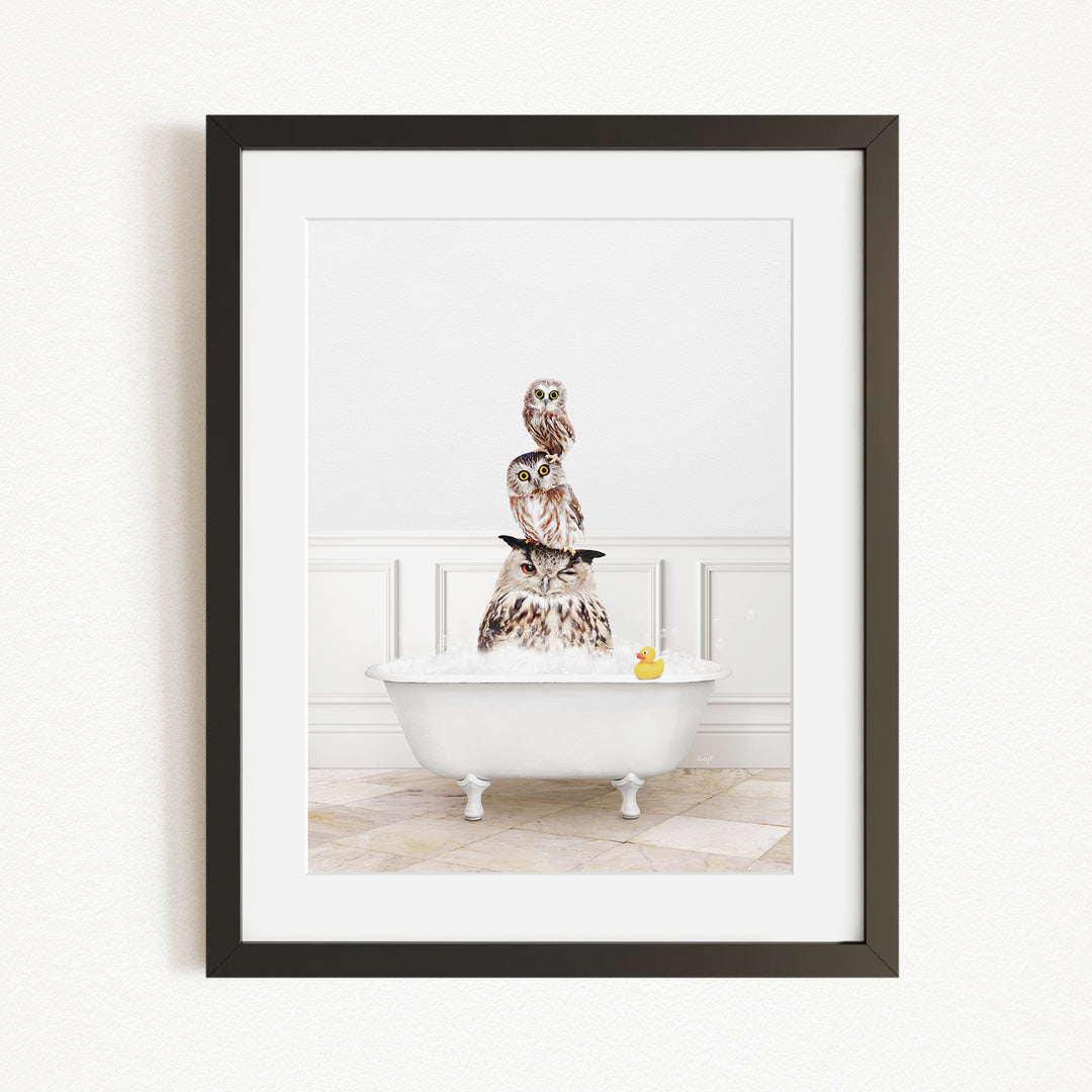 A framed image depicting a white bathtub filled with water, with a group of owls perched on top of it.