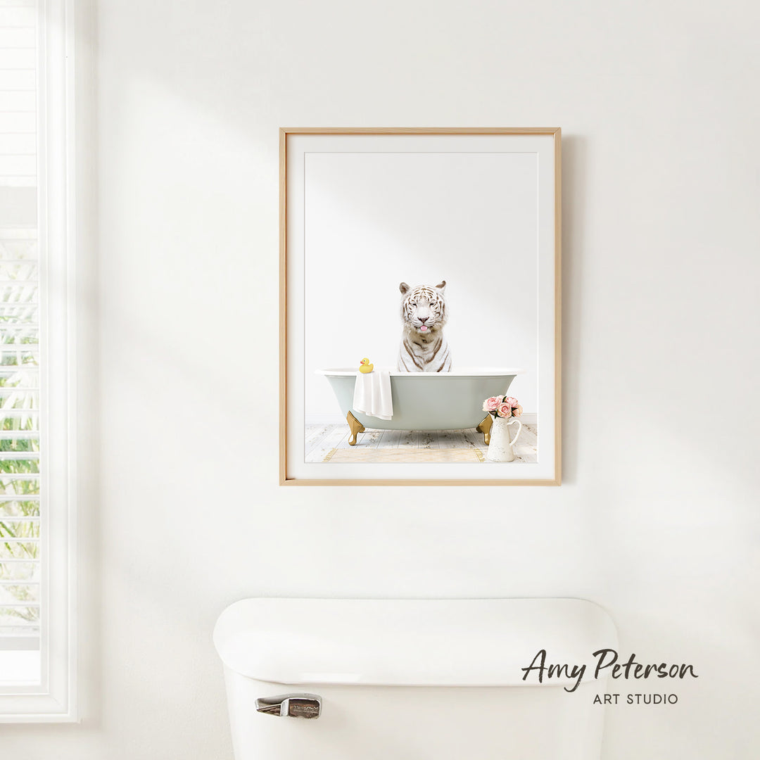 A framed image of a tiger sitting in a bathtub, surrounded by flowers and a vase, is displayed on a white wall in a bathroom.