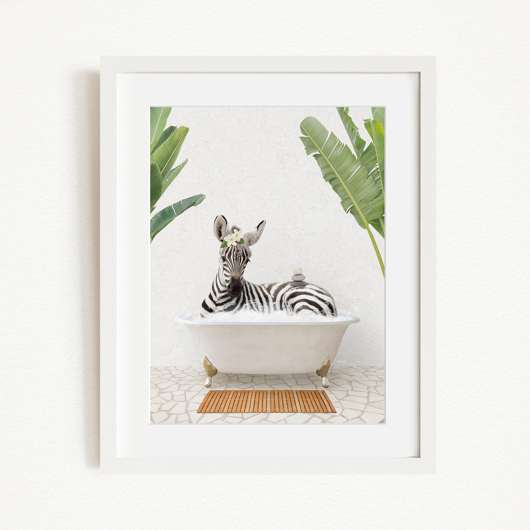 A zebra is sitting in a white bathtub, surrounded by tropical plants and a wooden mat on the floor.