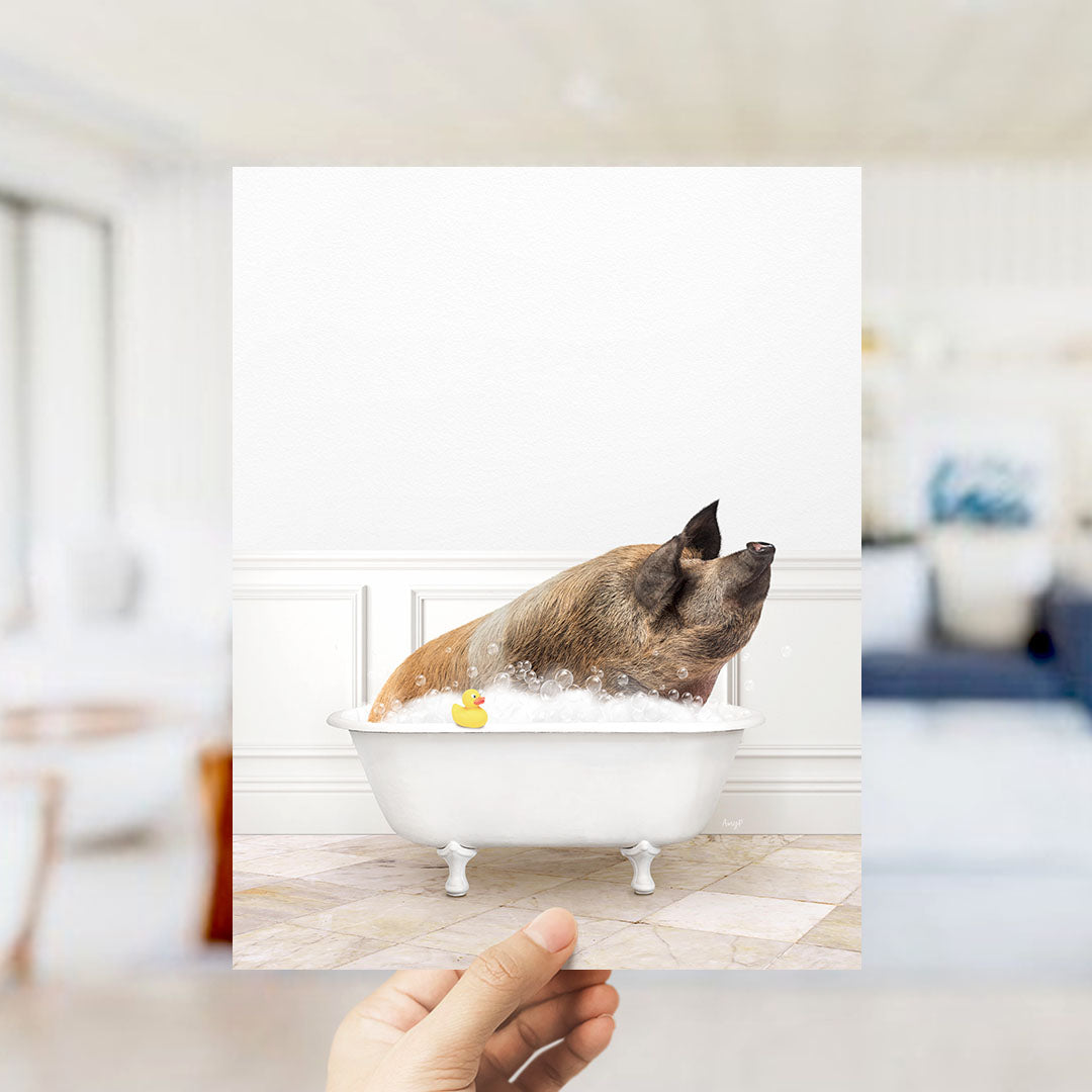 A hand holds up a framed image of a pig sitting in a bathtub, surrounded by a yellow rubber duck.