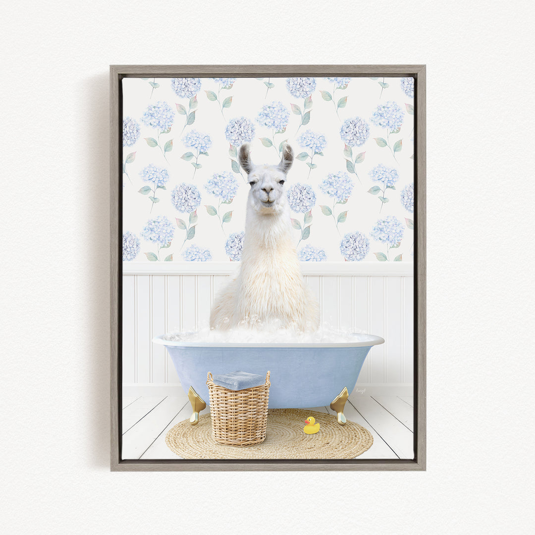 A white llama sitting in a blue bathtub filled with bubbles, surrounded by a wicker basket and a yellow rubber duck.