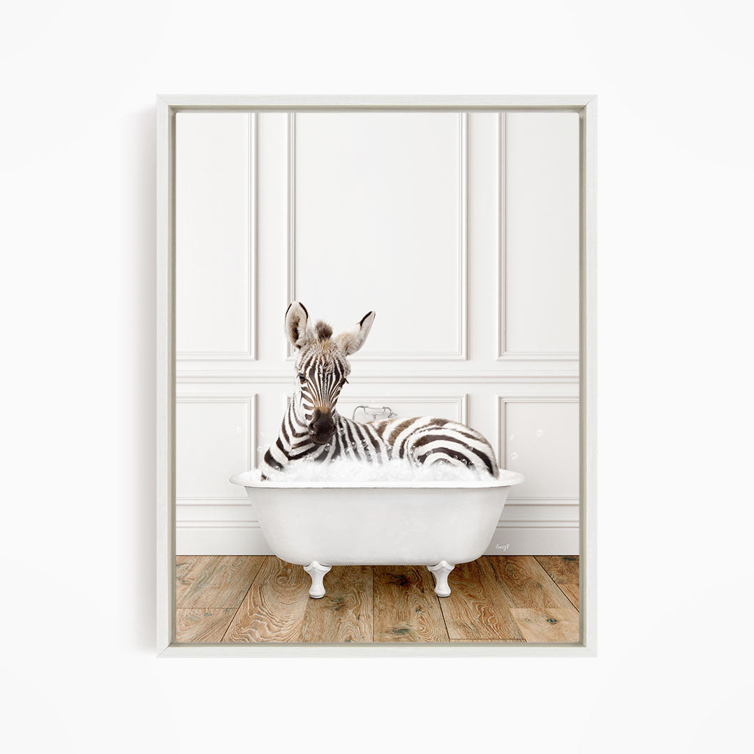 A zebra is sitting in a white bathtub, surrounded by a white wall and wooden floor.