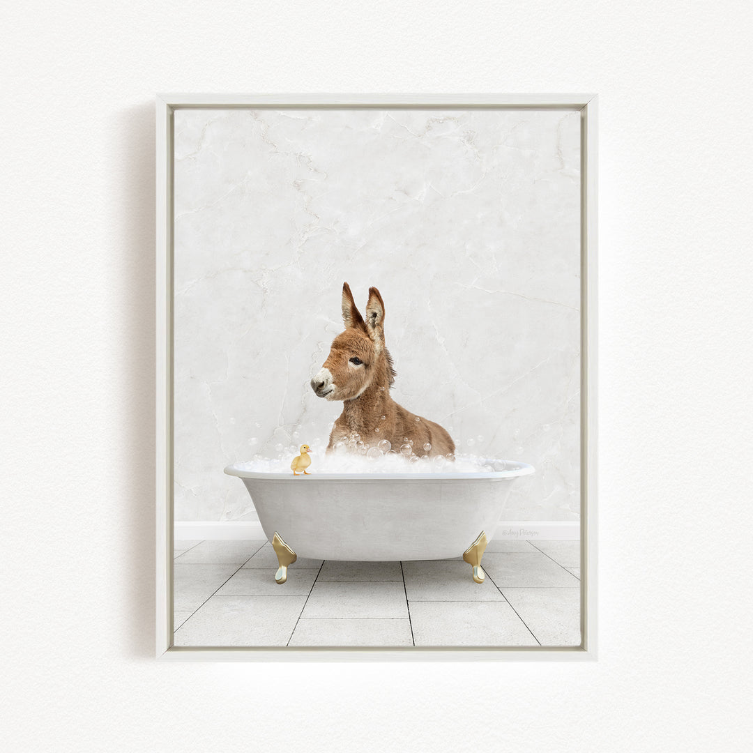 A donkey is sitting in a white bathtub filled with bubbles, surrounded by small yellow ducks.