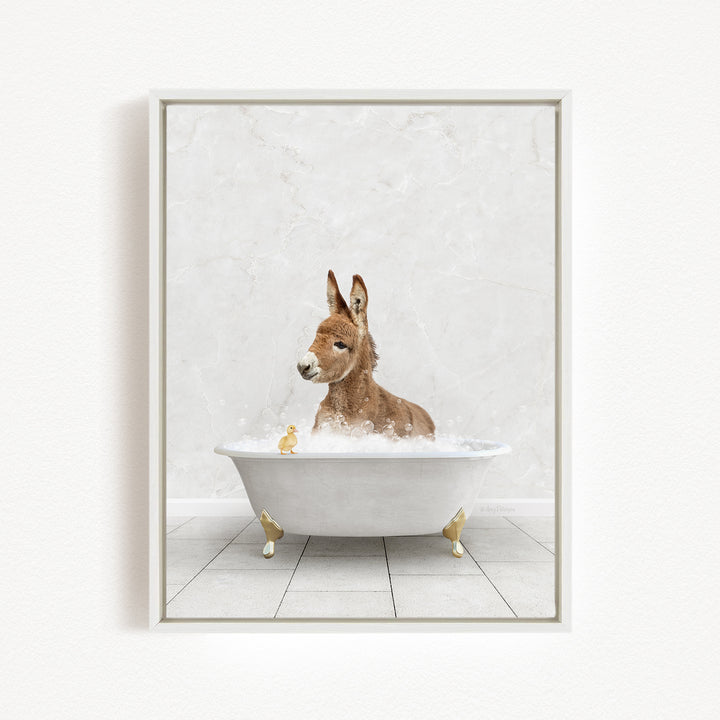 A donkey is sitting in a white bathtub filled with bubbles, surrounded by small yellow ducks.