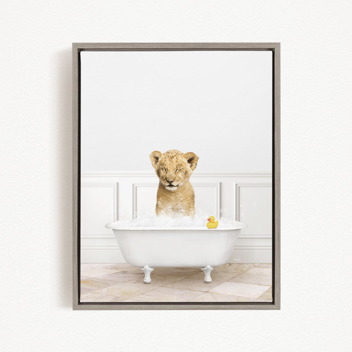 A young lion cub sitting in a white bathtub filled with bubbles, with a rubber duck floating nearby.