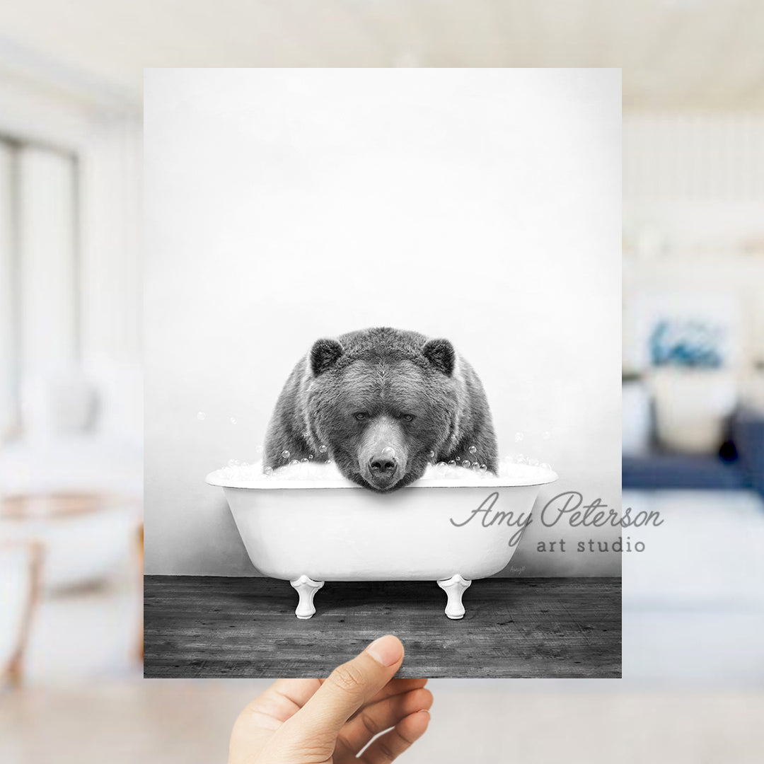 a hand holding up a black and white photo of a bear in a bathtub