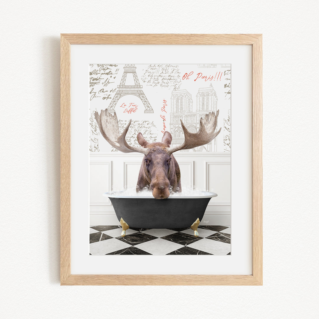A framed image depicting a moose sitting in a bathtub, with a Paris-themed background featuring the Eiffel Tower and other Parisian landmarks.