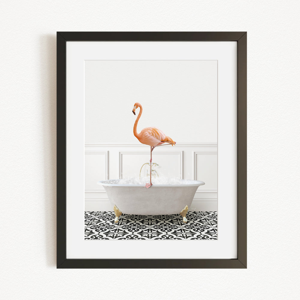 A framed image of a flamingo standing on the edge of a white bathtub filled with water, set against a white wall with a black and white patterned floor.