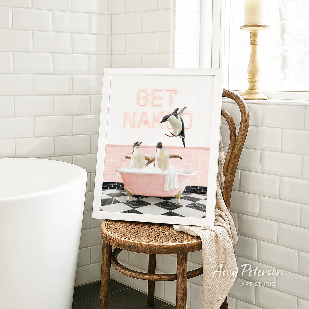 A framed image of penguins in a pink bathtub, with the text "GET NAKED" displayed on the frame.