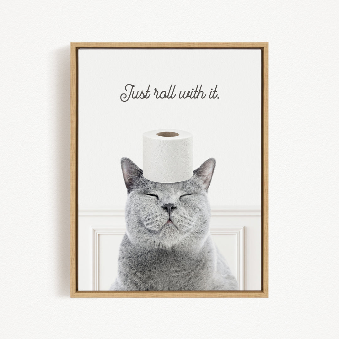 A gray cat with its eyes closed and a roll of toilet paper on its head, with the text "Just roll with it."
